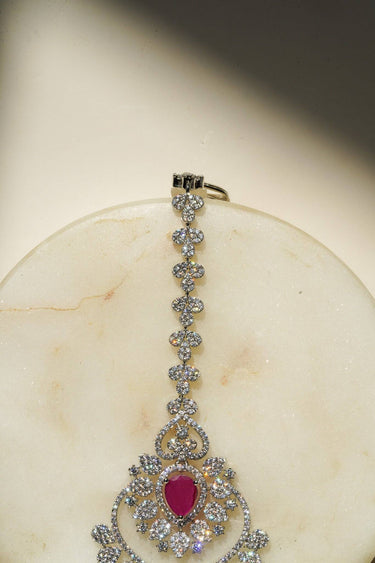 Close-up of the oversized Rhodium plated American Diamond Maang Tikka with ruby pink and green teardrop dangles