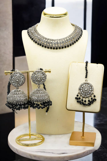 Urooj Necklace Set featuring zircon crystal choker, black-beaded Jhumka earrings, and Maang Tikka on gold stands. Classic Pakistani bridal jewelry.