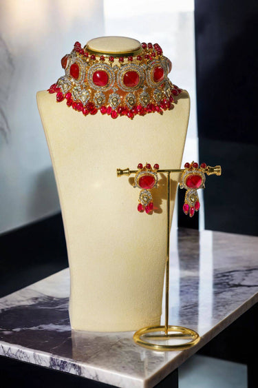 Sweta Choker Set - Diamante Necklace with bold red stones and intricate gold detailing, displayed on a bust with matching earrings.
