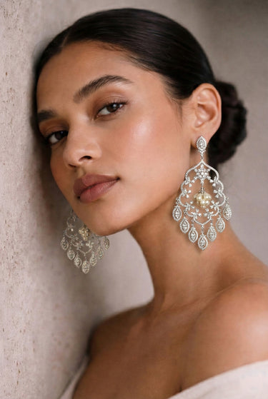 Woman wearing elegant silver earrings against a neutral background