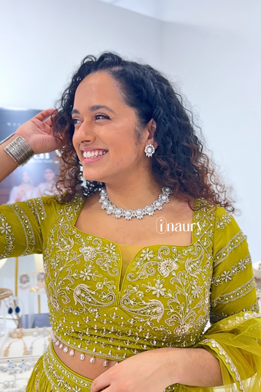 Model wearing the Mayesha Rhodium-Plated Pearl Necklace Set with a green embroidered lehenga, showcasing its elegant sparkle.