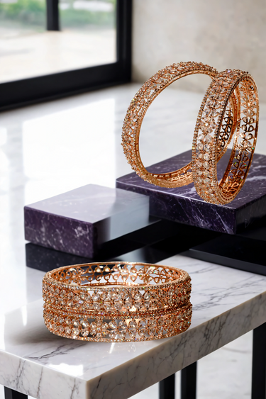 Myra Bangles Set - Rose Gold AD Bangles with floral petal design and white AD stone rims, displayed on marble and purple blocks.
