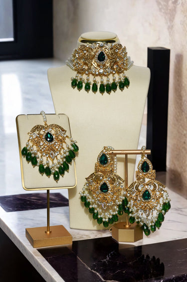 Noreen Choker Necklace Set - Elegant Pakistani Bridal Jewels in gold with green teardrop stones, displayed with matching earrings and tikka.