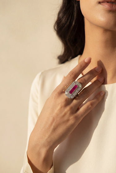 Close-up of a hand wearing a ruby with a red gemstone on a neutral background from Inaury