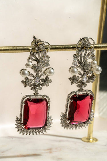 Side view of Aayat Statement Earrings in ruby red with a bold gemstone, pearl accents, and floral pavé setting. Oversized rhodium-plated earrings.