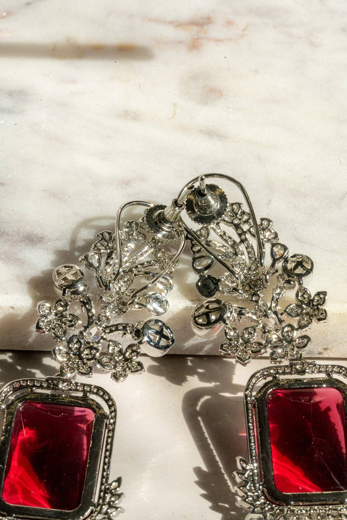 Back view of Aayat Statement Earrings in ruby red showing secure post closure and intricate rhodium-plated floral design.