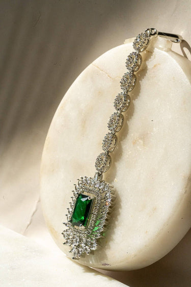 Side view of Alora Maang Tikka in rhodium finish showcasing intricate AD detailing and emerald green centerpiece.