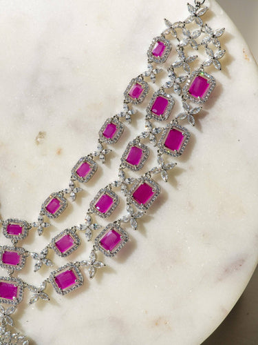 Amisha Triple Layer Diamante Accent AD Necklace Set in gold or rhodium-plated silver finish with color options of silver & sapphire blue, silver & green, gold & green, and silver & ruby, featuring floral and cushion cut stone patterns with matching earrings.