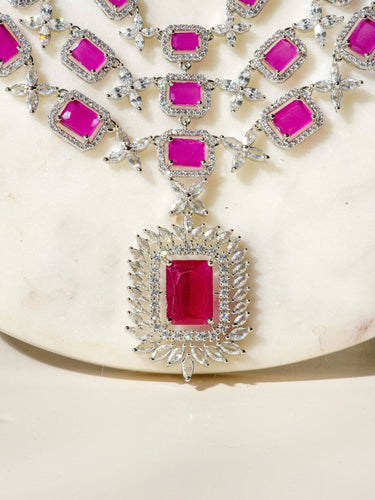 Amisha Triple Layer Diamante Accent AD Necklace Set in gold or rhodium-plated silver finish with color options of silver & sapphire blue, silver & green, gold & green, and silver & ruby, featuring floral and cushion cut stone patterns with matching earrings.
