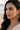 Woman wearing dangling AD Indian earrings with a blurred beach background
