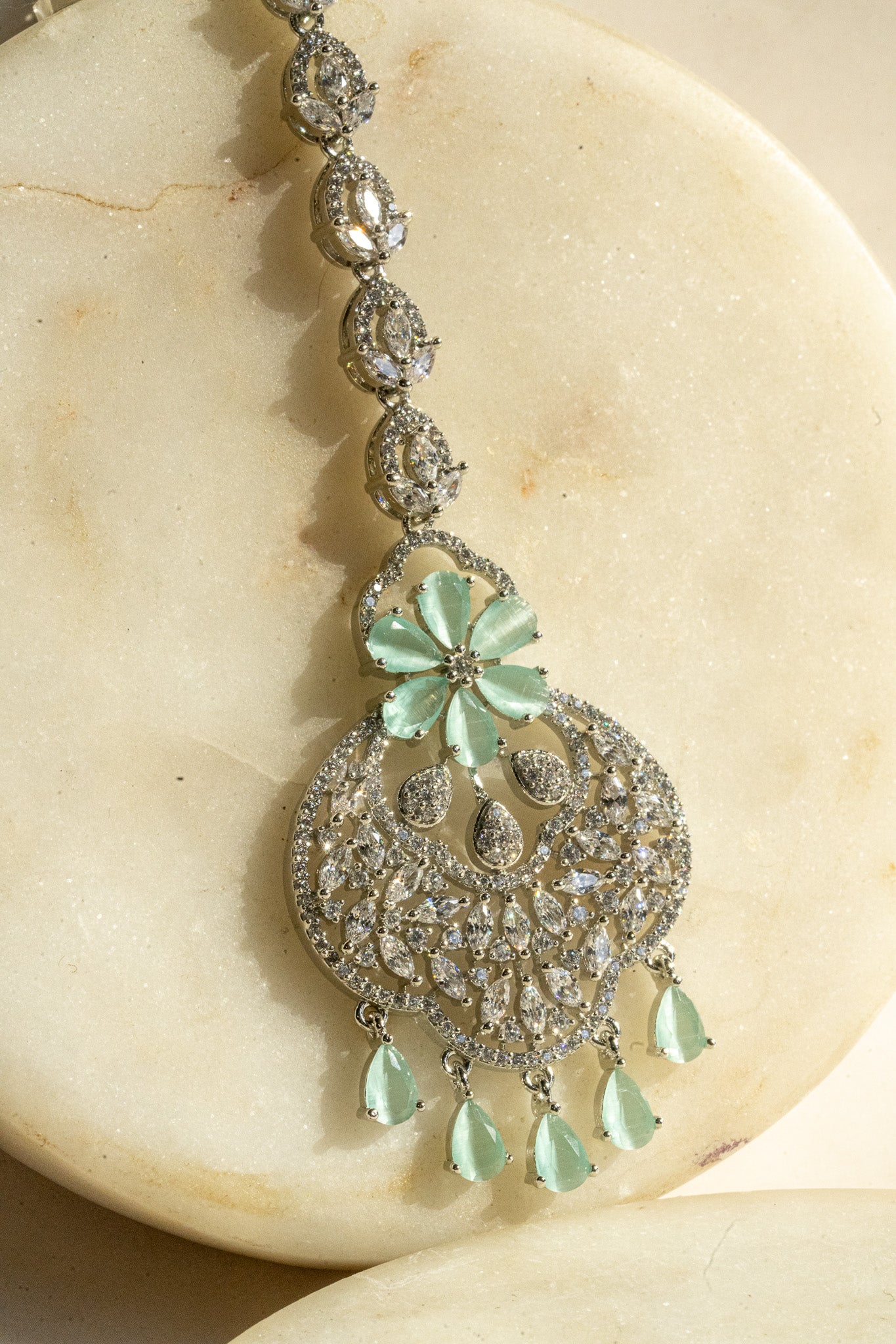 Rhodium-plated floral maang tikka with AD stones in a silver and mint from Inaury