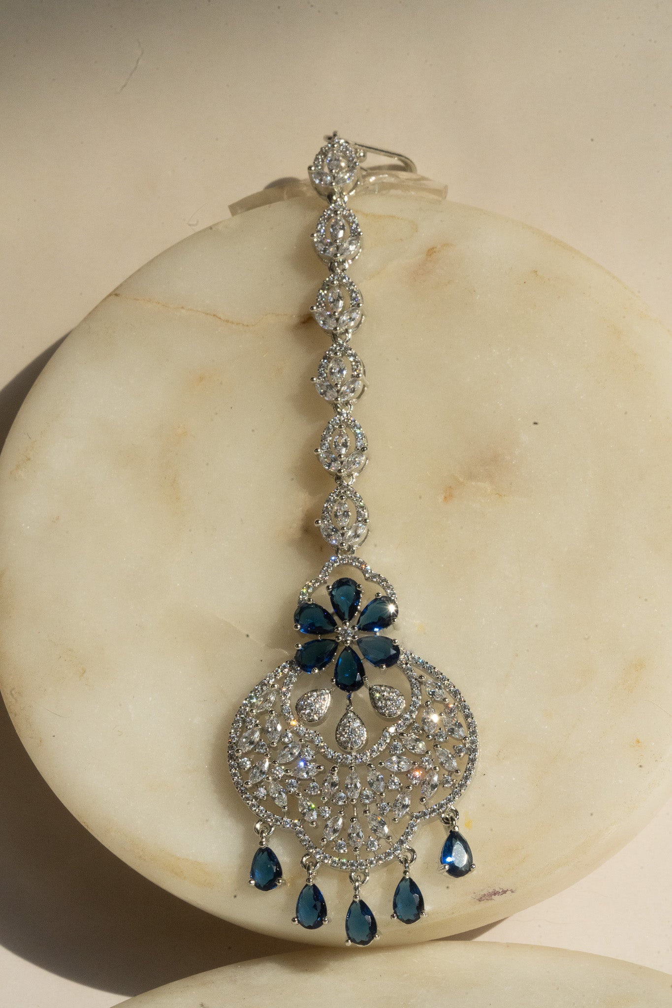 Rhodium-plated floral maang tikka with AD stones in a silver and sapphire blue from Inaury