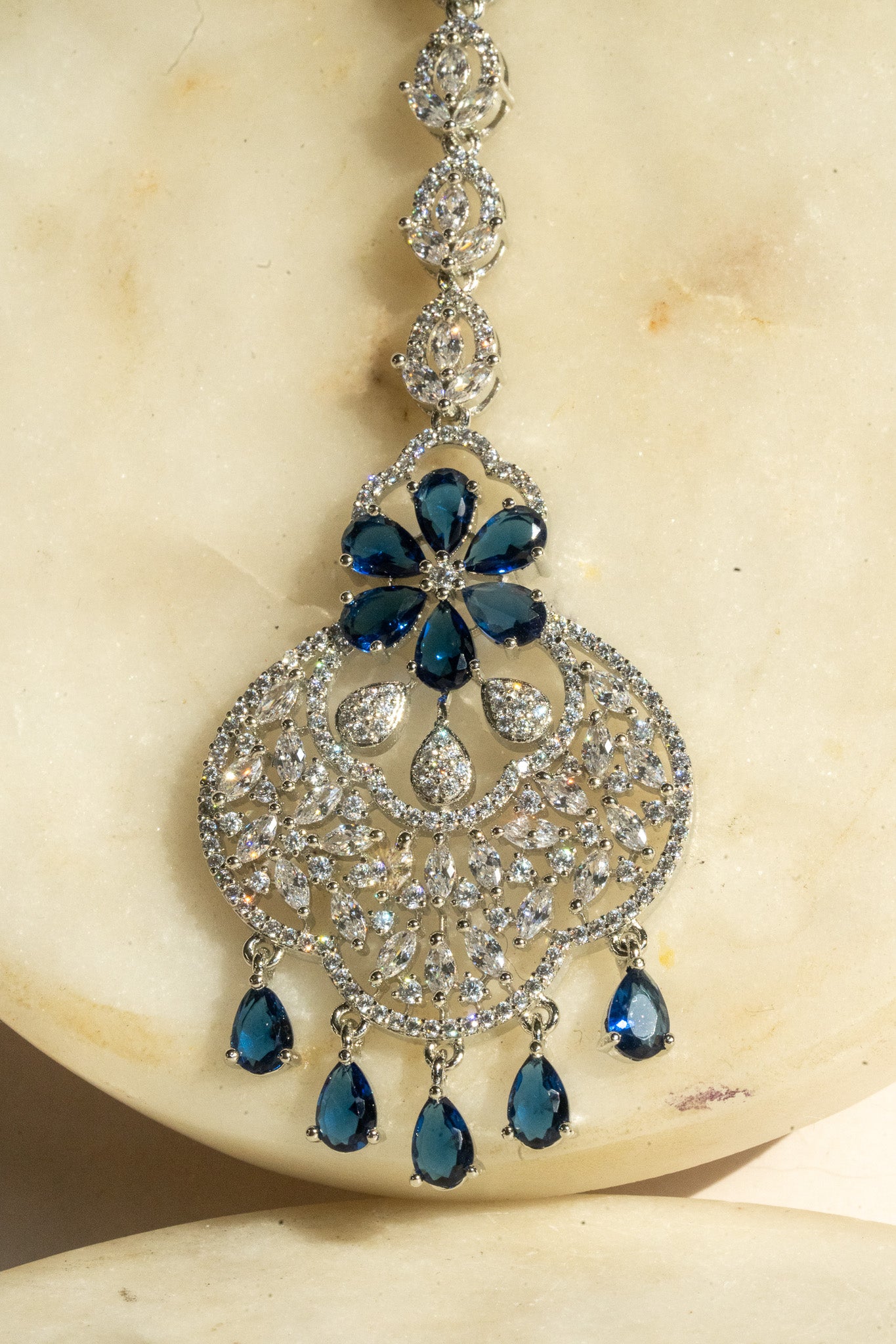 Rhodium-plated floral maang tikka with AD stones in a silver and sapphire blue from Inaury