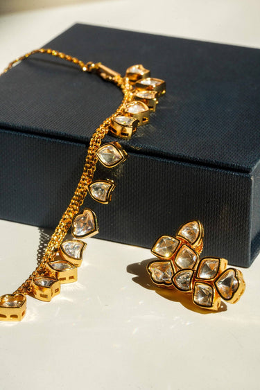 A macro product close-up showcasing the high-clarity clear glass heart-cut Kundan stones and polished gold-plated bezel frames of the Dilara jewelry set.