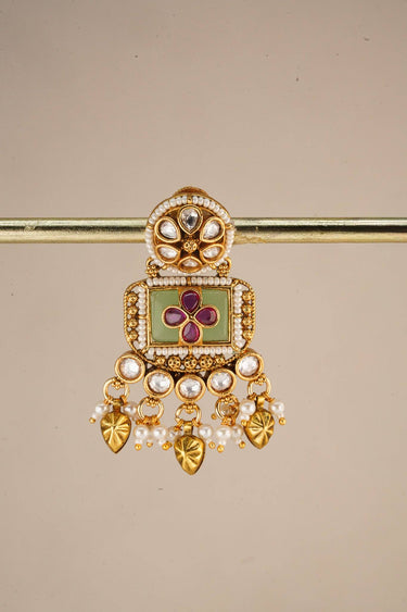A close up studio catalog shot focusing on a single Aadhya Kundan drop earring hanging on a display bar to highlight the fine seed pearl trim.
