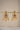 A clear front studio view of the pair of gold plated Aadhya Kundan glass polki earrings hanging symmetrically on a golden display bar.