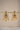A clear front studio view of the pair of gold plated Aadhya Kundan glass polki earrings hanging symmetrically on a golden display bar.