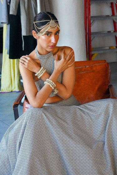 Close-up of the Aliya Jhumka Bangle Bracelet in antique gold with faux pearl beadwork, worn on a model's wrists with a grey South Asian outfit.