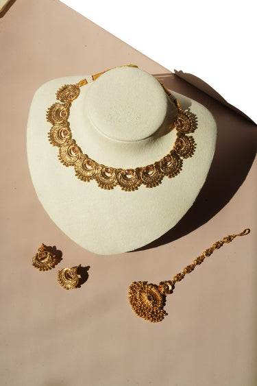 Ishani antique gold crescent necklace on a cream bust with matching earrings and maang tikka