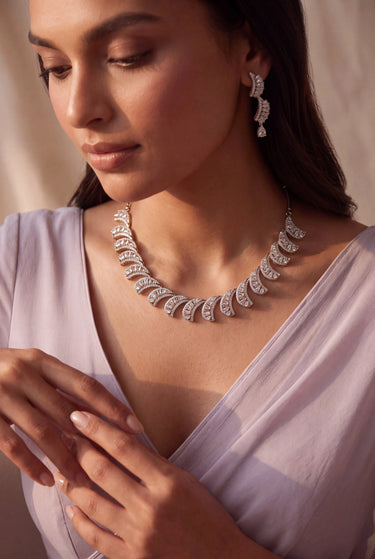 Close-up of Julie rhodium-plated crescent wave necklace and AD stone drop earrings worn with a lavender saree.