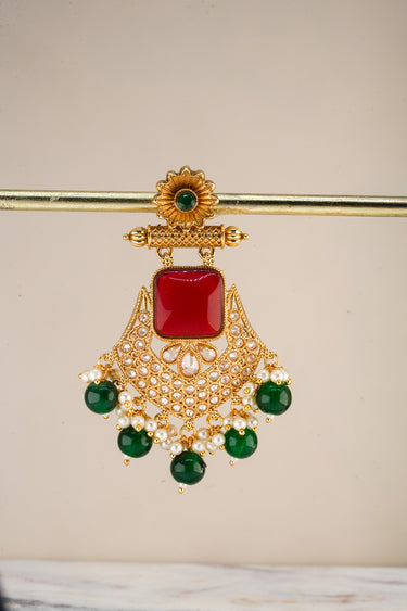 A crisp e-commerce catalog shot focusing on a single Kavya earring highlighting the intricate golden filigree, seed pearls, and contrasting green drops.