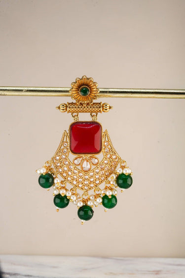 A crisp e-commerce catalog shot focusing on a single Kavya earring highlighting the intricate golden filigree, seed pearls, and contrasting green drops.