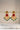 A symmetrical studio front view of the Kavya statement earrings featuring a vibrant ruby red centerpiece stone and emerald green cascading glass drops.