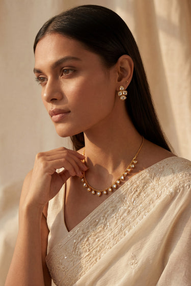 Side profile view of a model styling the delicate single-strand Kiara heart Kundan necklace over a white embroidered bridal saree.