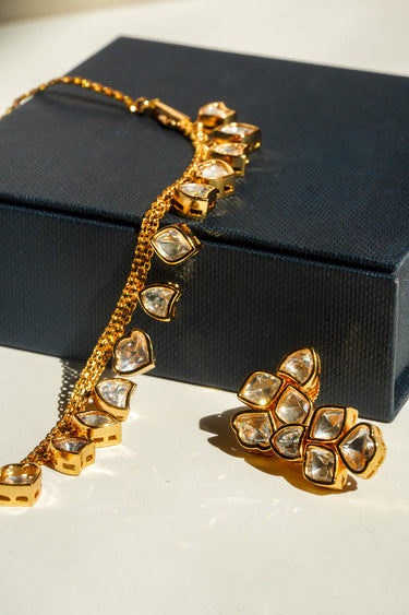 A macro product close-up showcasing the high-clarity clear glass heart-cut Kundan stones and polished gold-plated bezel frames of the Kiara jewelry set.