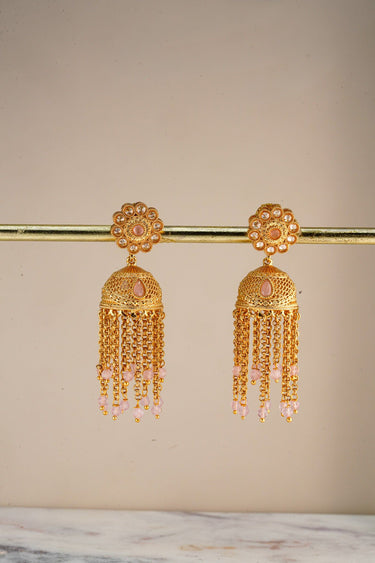 A pristine front studio catalog view of the pair of gold plated Lara handcrafted filigree jhumka earrings hanging symmetrically on a display stand.