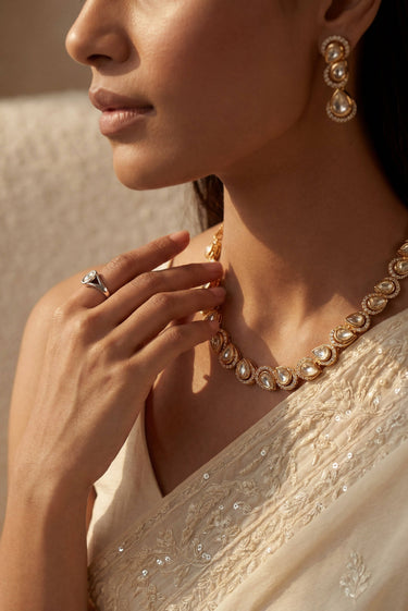 A side profile close-up portrait highlighting the fluid drape of the gold-plated Mehr teardrop Moissanite necklace and its matching triple-tier cascading drop earrings on a model.