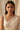 A close-up lifestyle portrait of a model wearing the Mehr gold-plated teardrop Moissanite necklace and matching triple-tier cascading earrings.