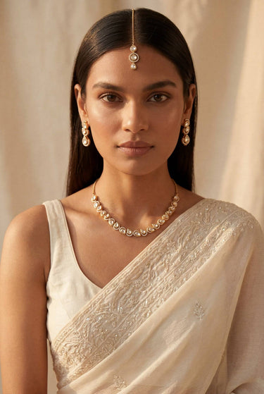A close-up lifestyle portrait of a model wearing the Mehr gold-plated teardrop Moissanite necklace and matching triple-tier cascading earrings.