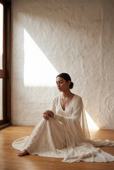 Left side profile of a model wearing the Sania rhodium-plated minimal necklace set, showcasing the cascading triple layered Kundan chain and hinged drop earrings.
