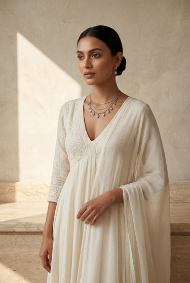 A wide landscape portrait layout of a model wearing the Sania minimalist triple-chain Kundan necklace set with a dark evening dress.