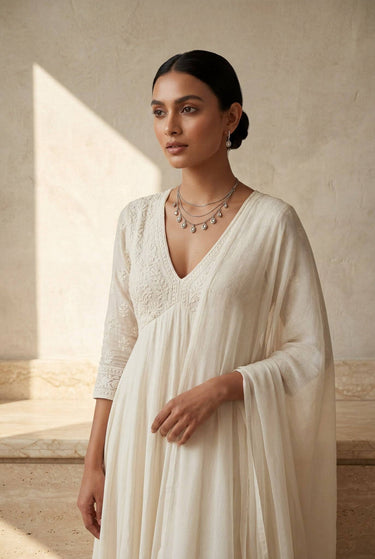 A wide landscape portrait layout of a model wearing the Sania minimalist triple-chain Kundan necklace set with a dark evening dress.