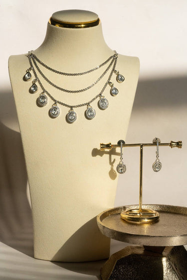 The complete Sania rhodium-plated minimalist Kundan necklace and hinged drop earring set displayed together on a white platform.