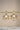 A crisp front studio view of the pair of Zoe mehndi gold drop earrings showcasing the symmetrical layout of crystals on a display bar.