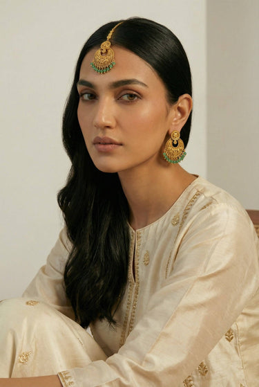 Inaury Gurleen Chandbali & Maang Tikka Set worn by model in ivory kurta — side profile showing full chandbali crescent earring with emerald ghungroo drops and gold tikka