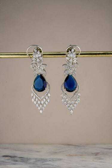 Inaury Nimisha AD Drop Earrings Sapphire Blue displayed on earring stand — rhodium-plated South Asian statement earrings with AD marquise cascade and teardrop center