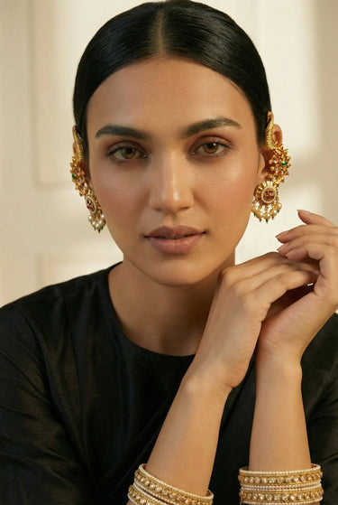 Close-up of Inaury Tripthi Ear Climber Ruby Emerald on model — gold-plated peacock motif with ruby-pink and emerald kundan stones and pearl drops