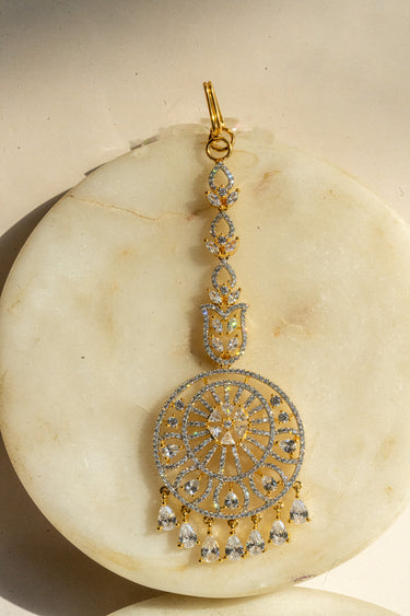 Round-shaped maang tikka with teardrop AD stones in gold plating with white accents from Inaury