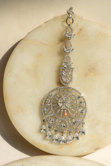 Round-shaped maang tikka with teardrop AD stones in rhodium plating with white accents from Inaury