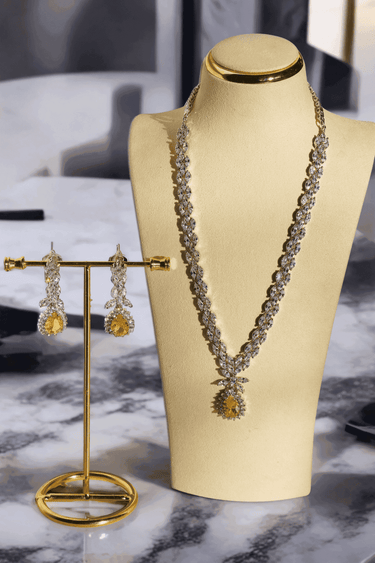 Lina Long Diamante Accent AD Necklace Set - Rhodium-plated with white AD stones, featuring intricate patterns and pendant-like centerpiece, available in silver & sapphire blue, silver & purple, and silver & citrine yellow, with matching dangling earrings.