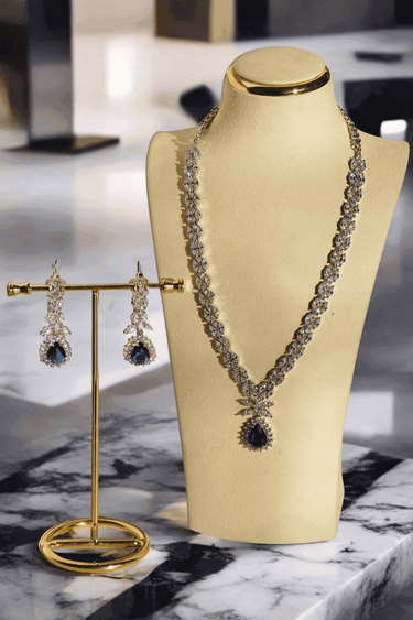 Lina Long Diamante Accent AD Necklace Set - Rhodium-plated with white AD stones, featuring intricate patterns and pendant-like centerpiece, available in silver & sapphire blue, silver & purple, and silver & citrine yellow, with matching dangling earrings.