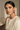 Woman wearing a beige top with floral Navratan statement stud earrings against a neutral background