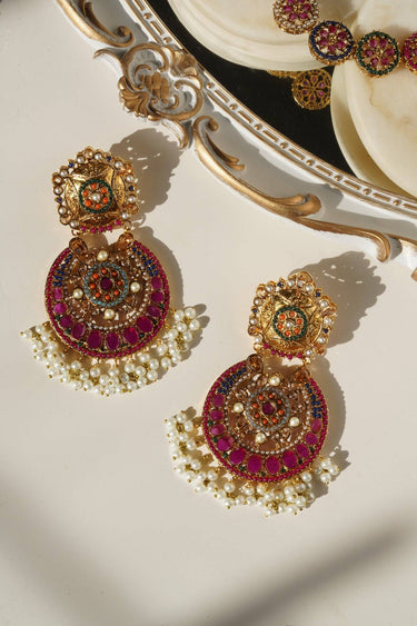 Adiva Statement Earrings with gold plating, pink stones, and pearl fringe, styled on a cream marble background.