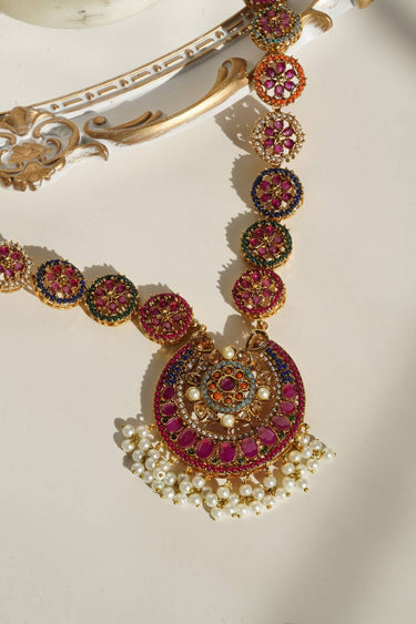 Close-up of Adiva Gold Mala Necklace pendant with multi-color stones and pearl moti, highlighting detailed craftsmanship.