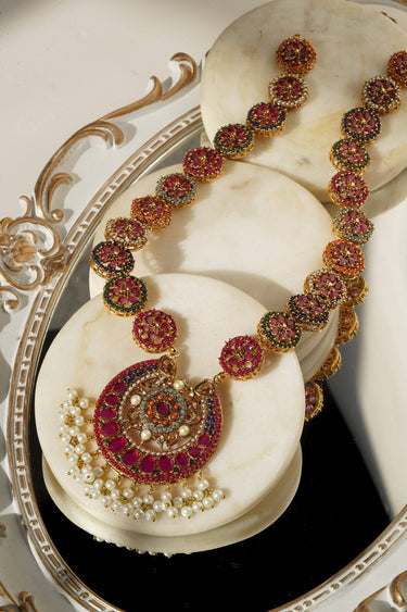 Adiva Long Necklace Set with gold plating, colorful stones, and pearl detailing, elegantly arranged on a mirrored tray.
