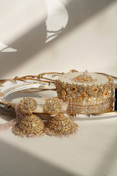 Ayesha Choker Necklace Set with pink beads and floral detailing, laid out with earrings and Maang Tikka on a marble tray.